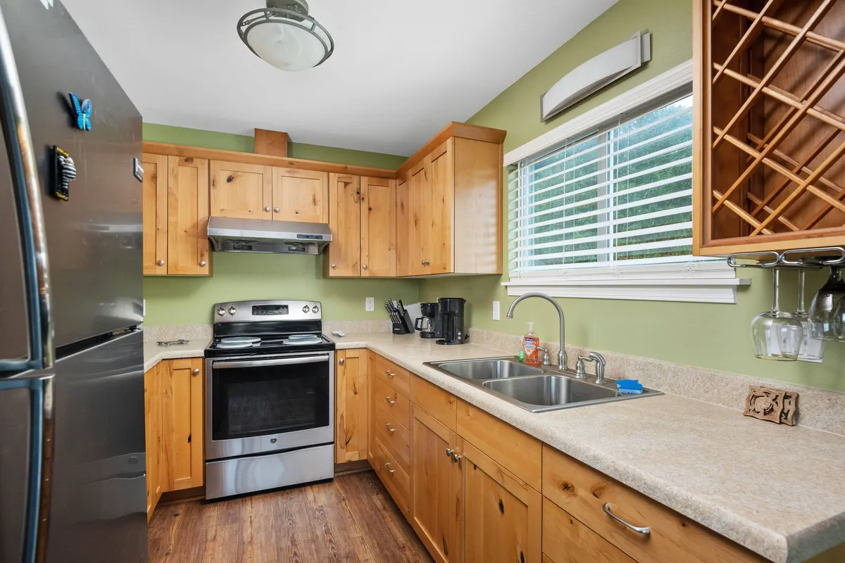 The kitchen features modern stainless steel appliances, ample cabinetry, a double sink, and a wine rack. The setup suggests convenience for cooking and socializing, with amenities that cater to a group’s needs.