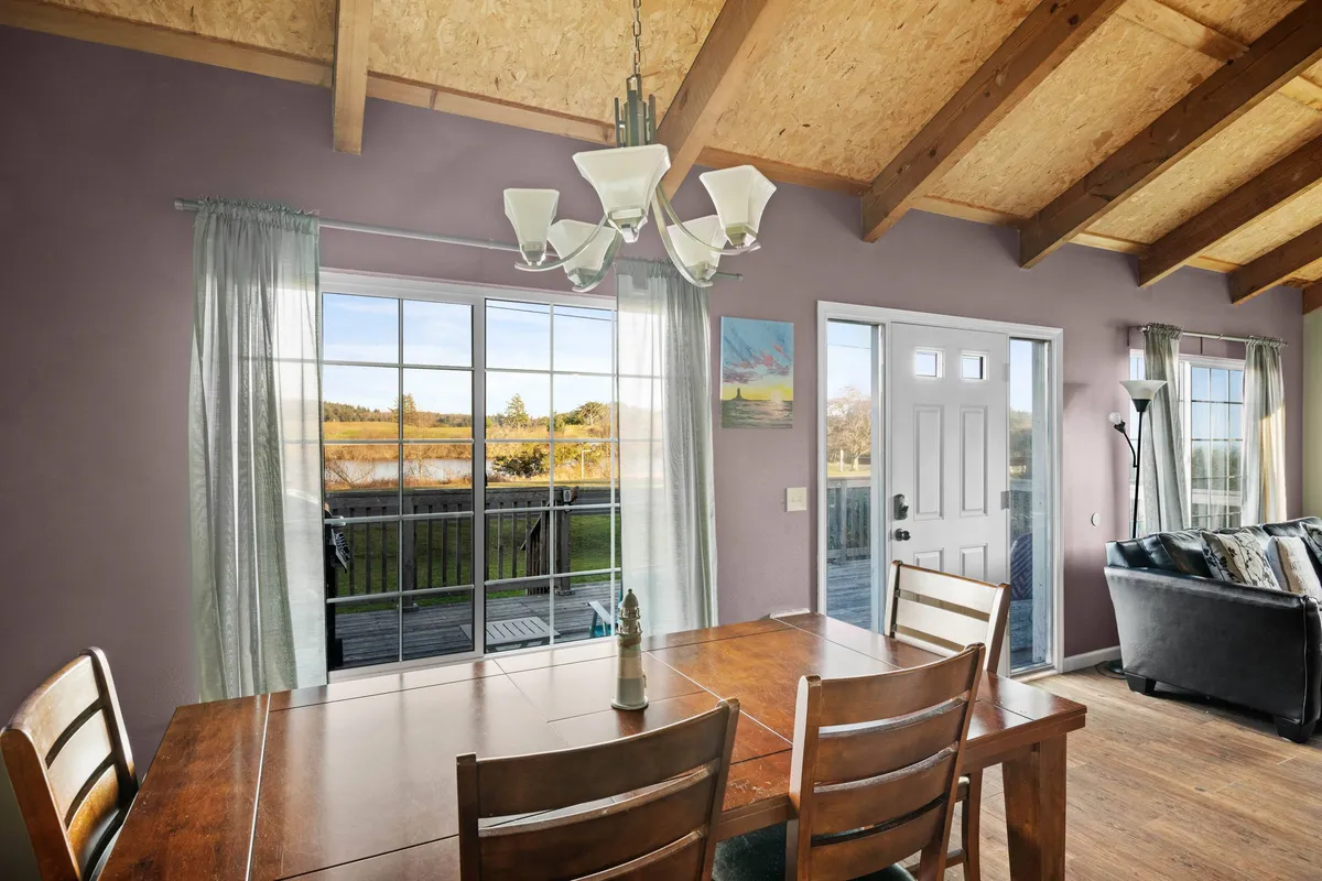 A spacious dining area with a large table that seats up to ten, surrounded by windows that offer views and fill the space with light. The image also hints at the adjacent living area, reinforcing the open-concept layout.