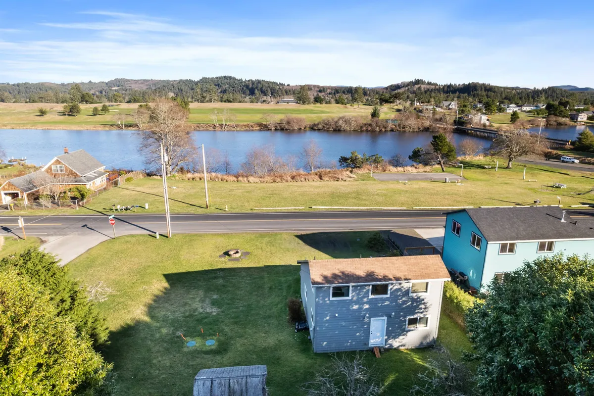 A relaxed riverside view showing houses nestled among greenery, a quiet road, and the river winding through. The area looks ideal for walking, biking, and wildlife watching. The image evokes a sense of community and leisure, suitable for nearby park events or riverside activities.