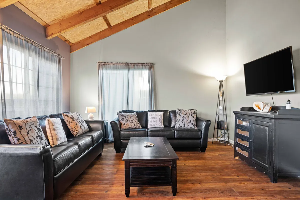 A cozy living room interior with plush leather sofas, a coffee table, and a TV softly lit by a warm lamp. The inviting setup encourages movie nights, board games, and intimate gatherings, providing a comforting retreat for rainy or cool days.